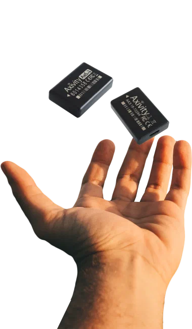 A hand holding an AX3 accelerometer, showing its size against the palm